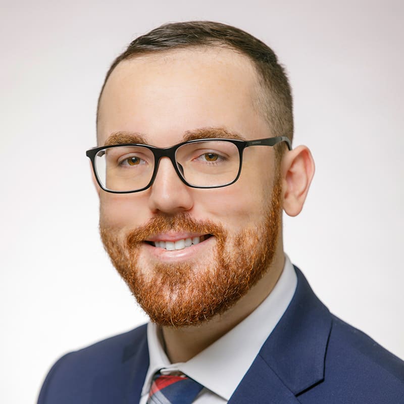 Portrait of Jack LaFrance in a gray shirt, red tie, and dark blue blazer.