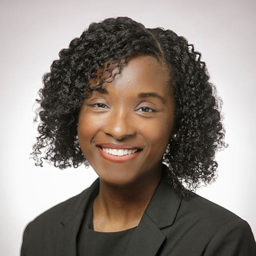 Smiling person in a black blazer and blouse